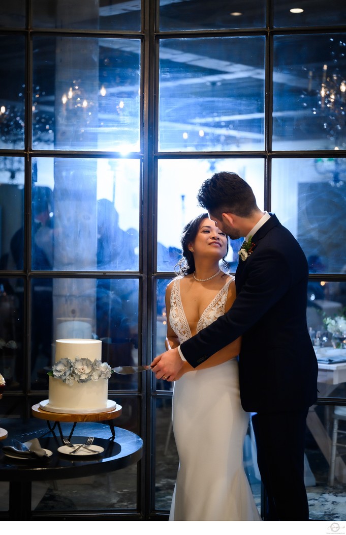 Couple Cutting Wedding Cake with Blue Uplighting