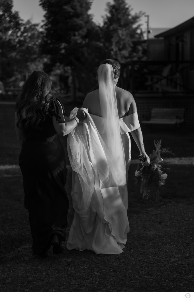 MOH Holding Brides Dress While Walking at Belcroft 
