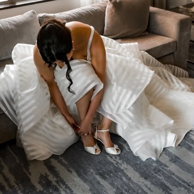 Bride in Ball Gown Putting on Her Wedding Shoes
