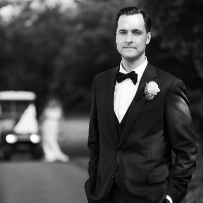 Groom Portrait with Bride in Background