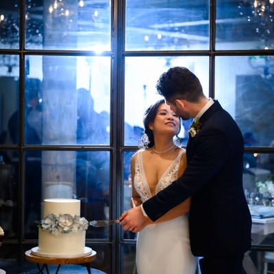 Couple Cutting Wedding Cake with Blue Uplighting