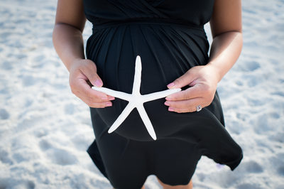 maternity photos with a black dress at the beach in jacksonville