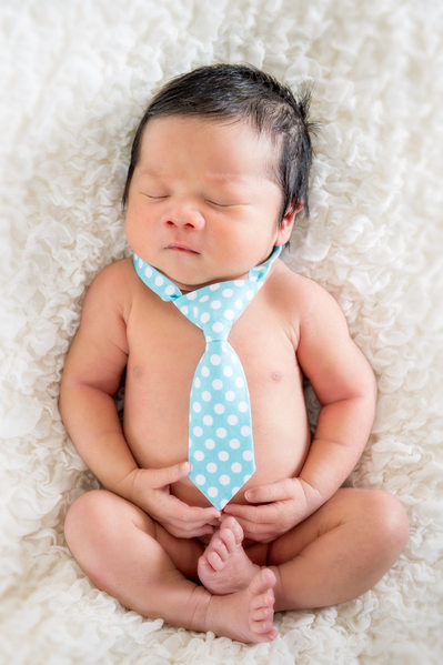 newborn boy with blue tie and white blanket