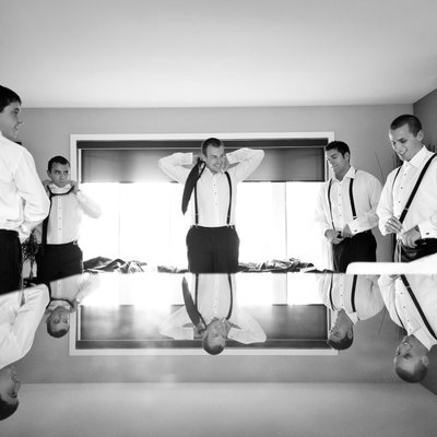Groomsmen getting ready reflected on a table surface.