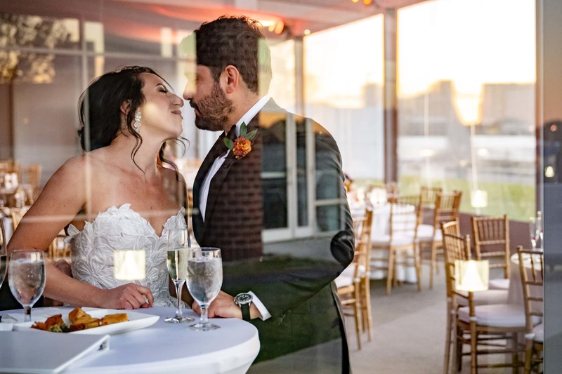 Wedding couple go in for a kiss with city reflections at sunset