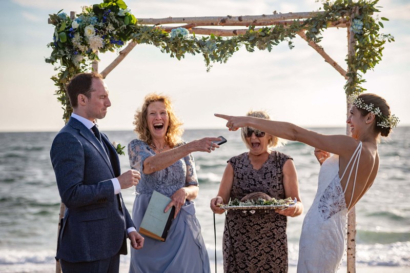 Joyful ocean ceremony moment with bride and groom and their moms