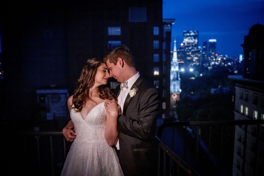 Night portrait at The Omni Parker House of a wedding couple overlooking the Boston skyline.