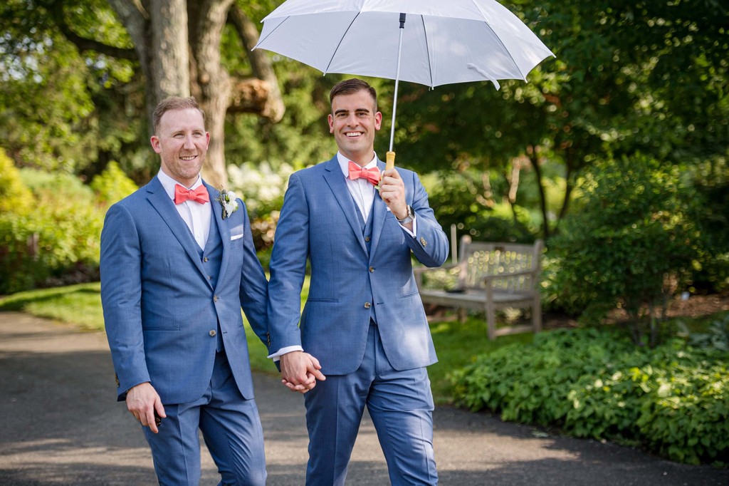 Grooms walking with umbrellas on their wedding day at Elm Bank