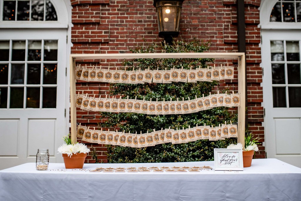 Escort card display with floral backdrop at Elm Bank wedding