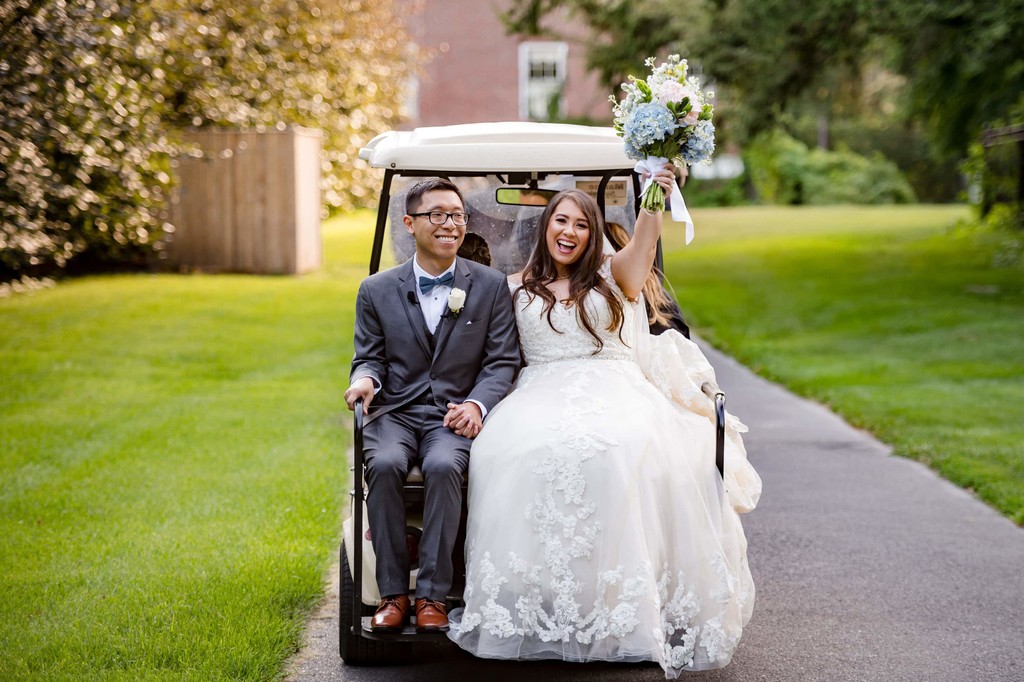 Bride and groom riding in a golf cart at Elm Bank wedding