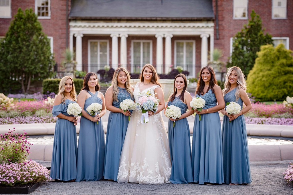 Bridesmaids in blue posing in front of Elm Bank mansion