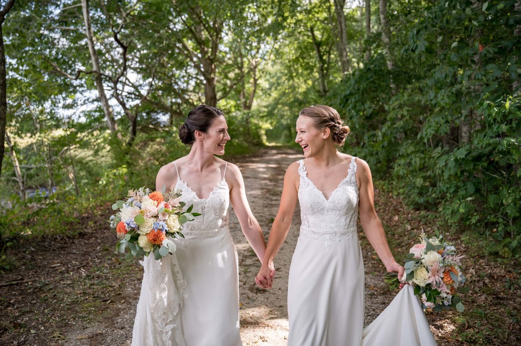 Same-sex wedding couple walking and laughing in the woods