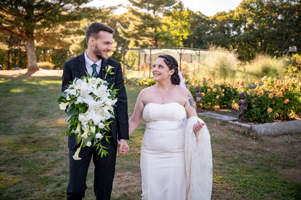 Bride and groom walking through gardens at Fern Hill Barn