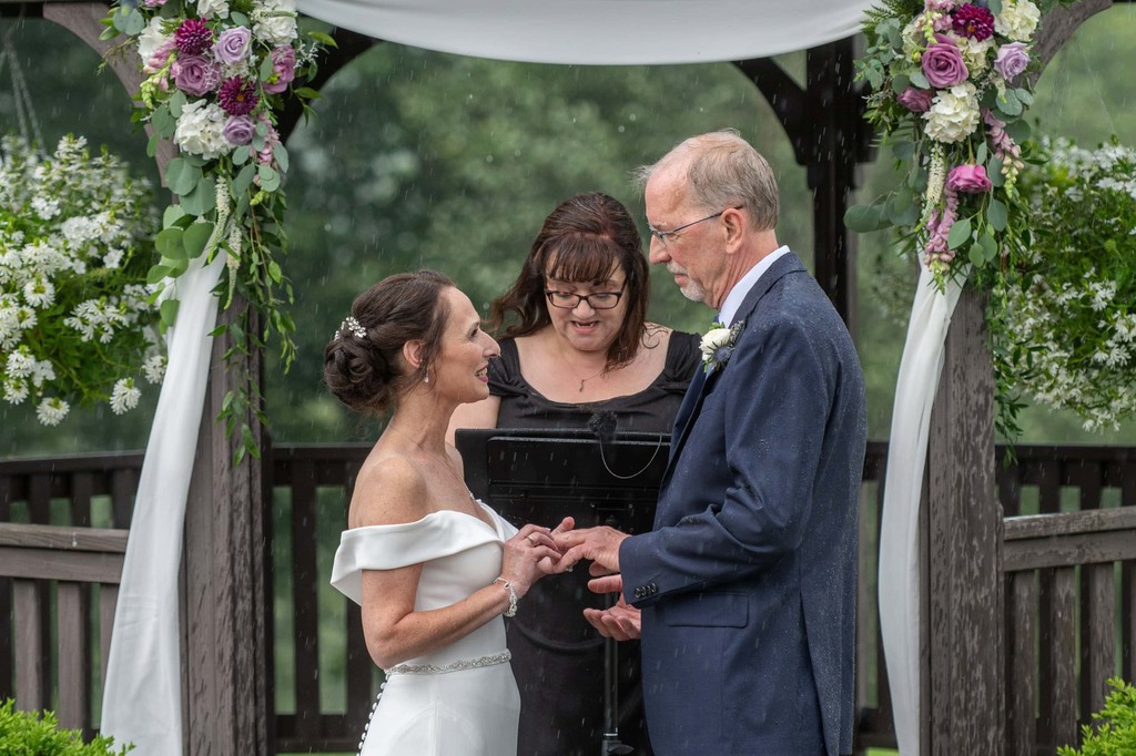 Emotional vow exchange during the rain at Fern Hill Barn arbor