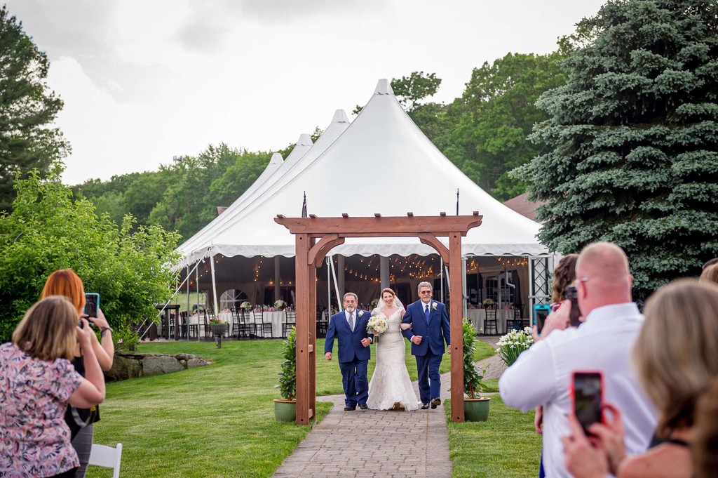 Bride walks down the aisle with her 2 dads at a Fern Hill Barn wedding