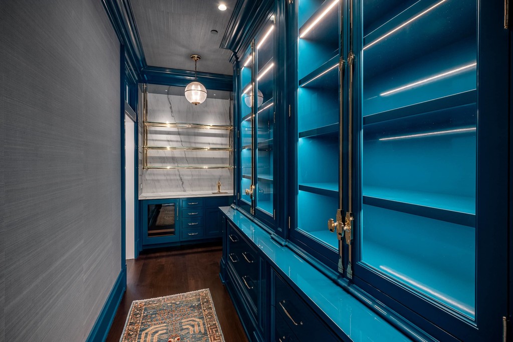 Built-in blue pantry with brass fixtures and wood desk