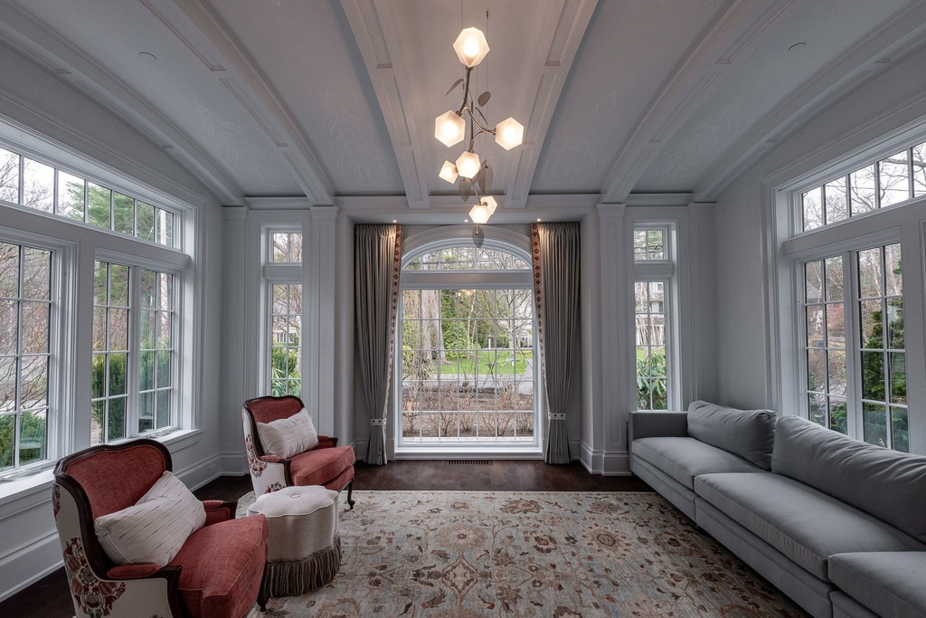 Sunlit sitting room with large windows and chandelier
