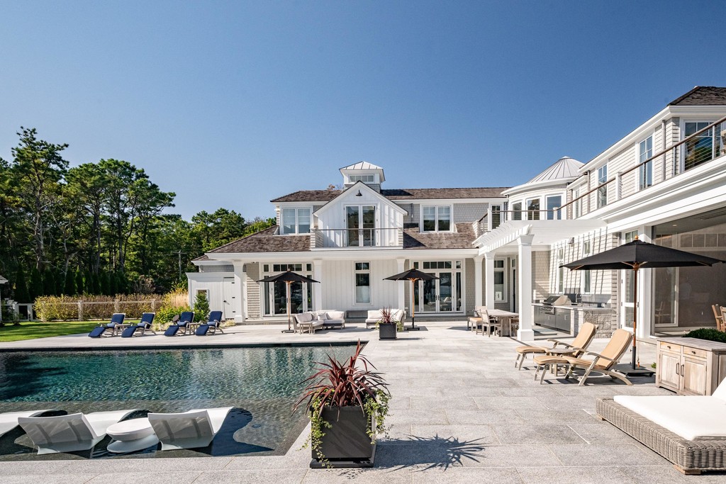 Backyard patio with pool and elegant white home exterior