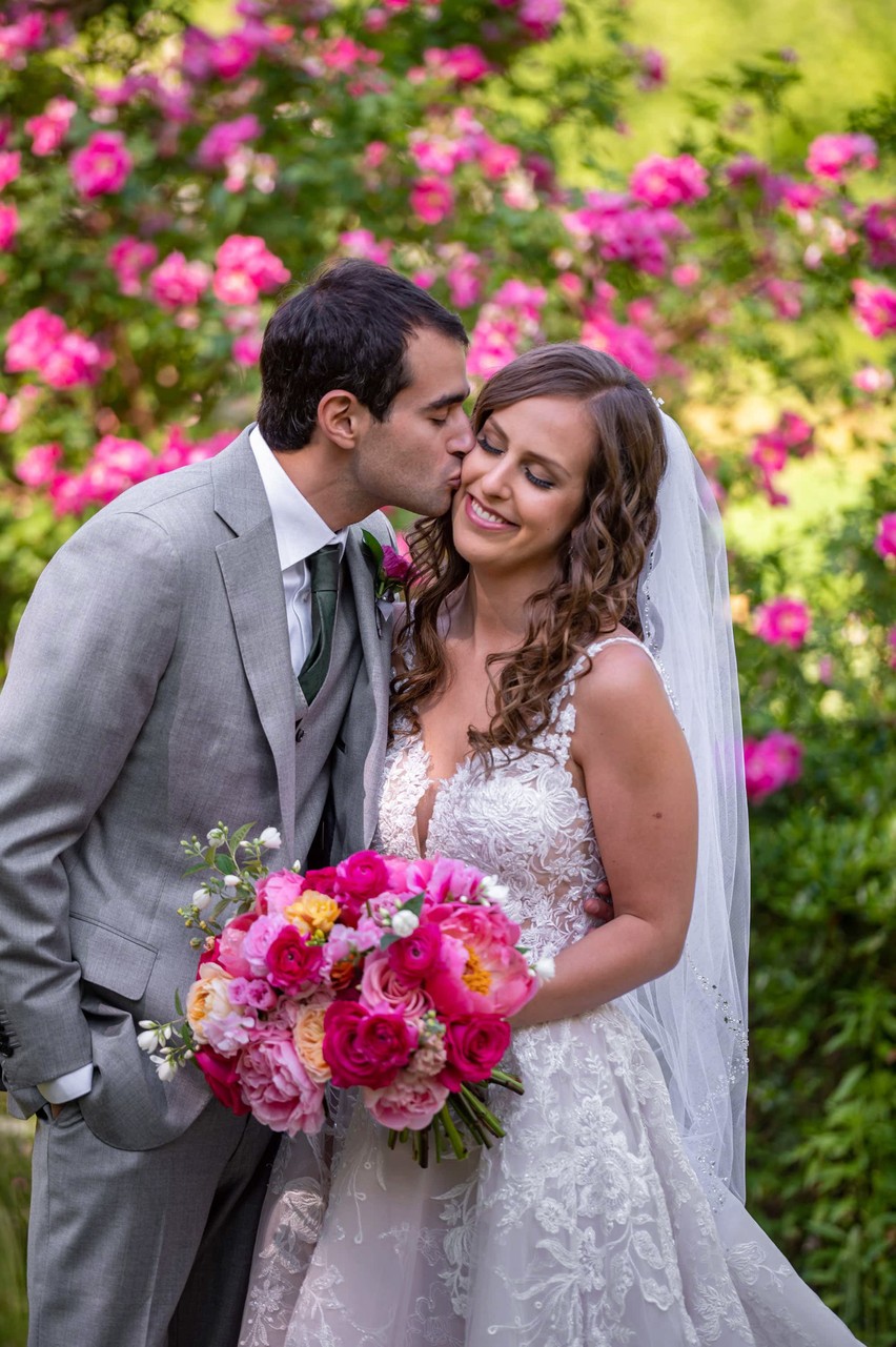 Bride and groom smiling in front of pink floral arch at Elm Bank weddings