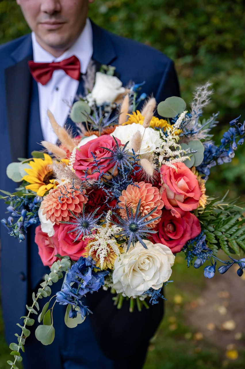 Groom holds colorful bouquet at Fern Hill Barn wedding