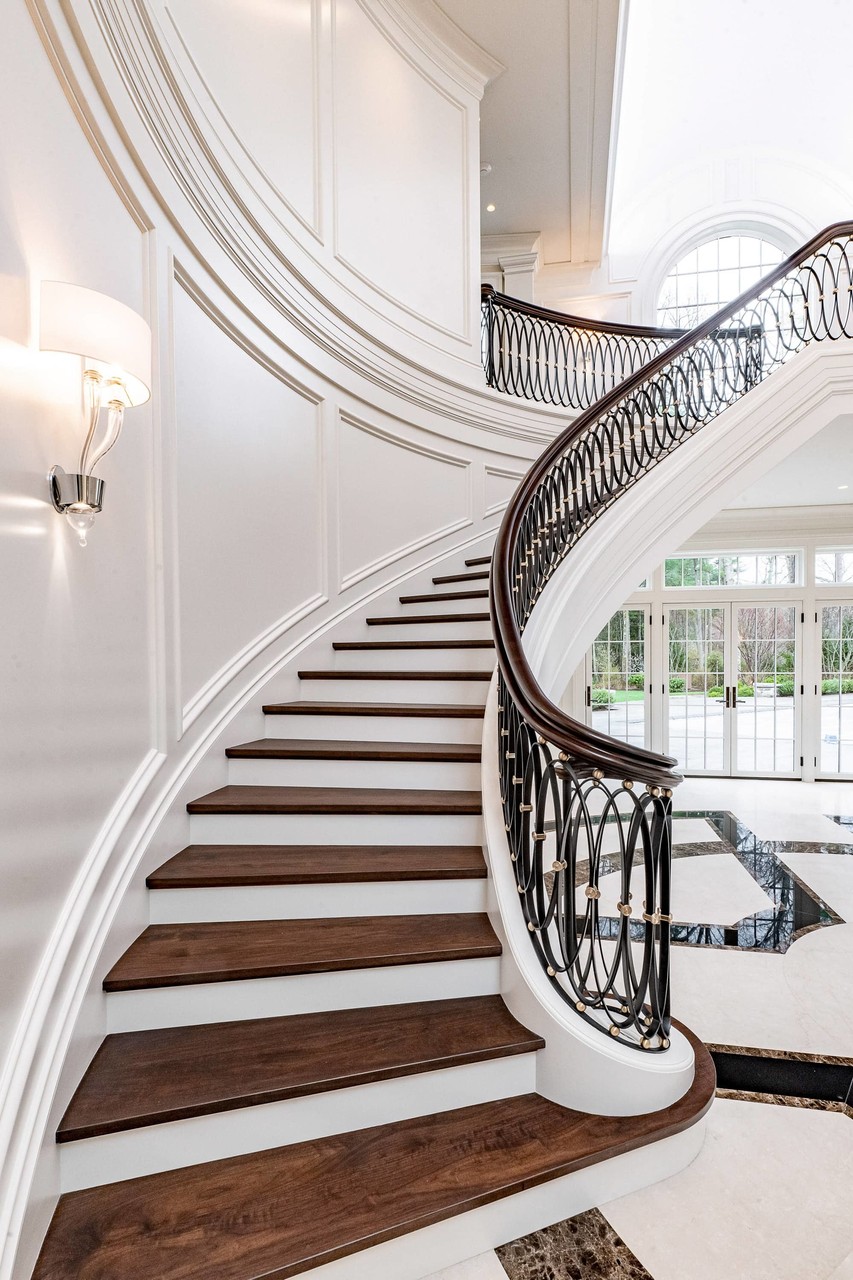 Grand spiral staircase with custom woodwork trim and ironwork