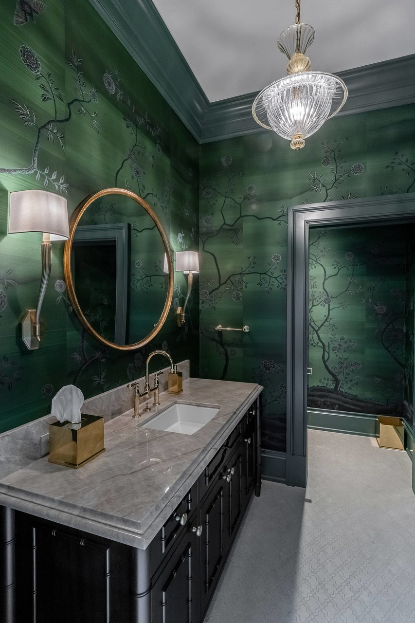 Moody powder room with green tile and brass mirror