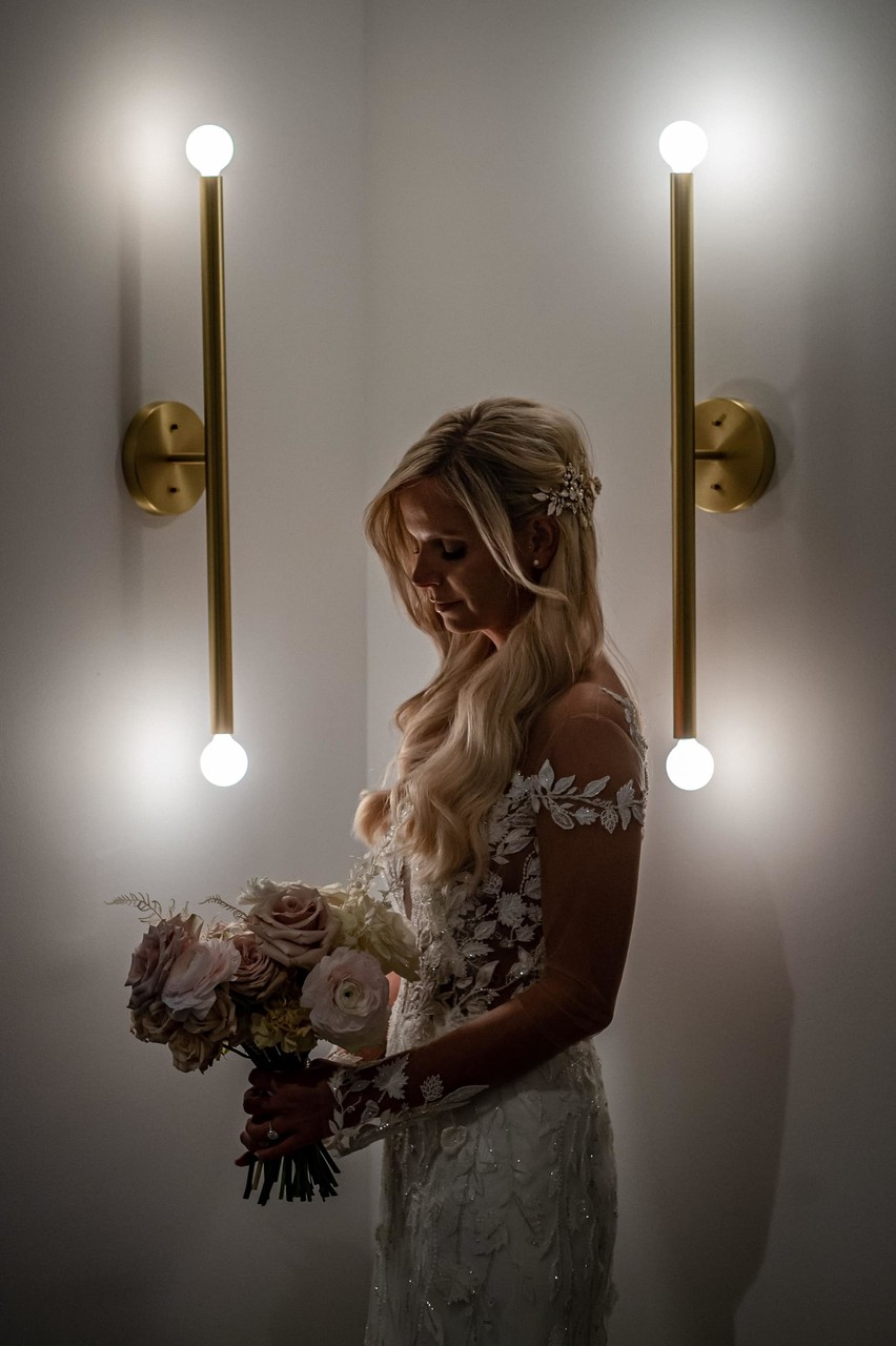 Bride holding bouquet near modern wall sconce