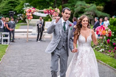 Just married couple cheering while walking down the aisle at Elm Bank wedding