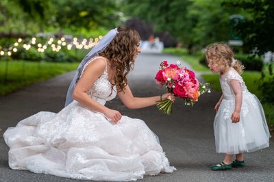 Bride kneeling to share a sweet moment with flower girl at Elm Bank wedding