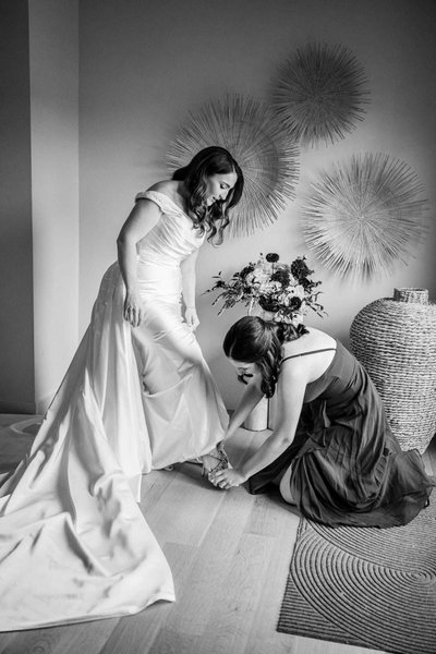 Candid moment of the bride getting her shoes on in the bridal suite