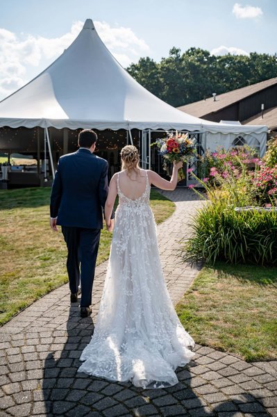 Bride and groom walking toward tent – Fern Hill Barn path