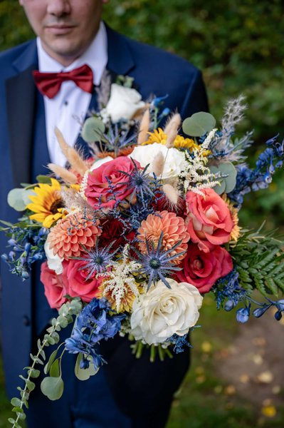 Groom holds colorful bouquet at Fern Hill Barn wedding