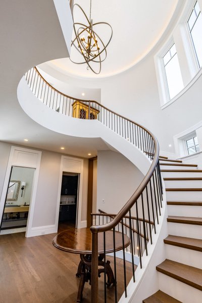 Sweeping staircase with modern chandelier and skylight