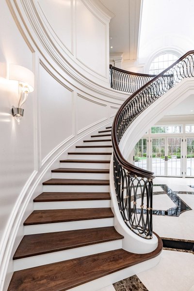Grand spiral staircase with custom woodwork trim and ironwork