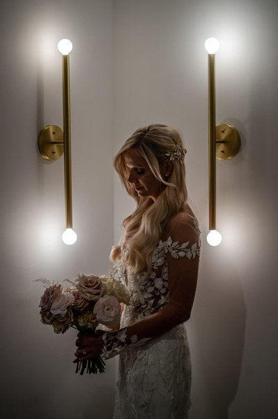Bride holding bouquet near modern wall sconce