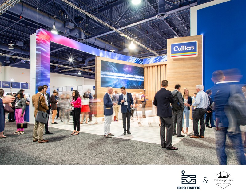 people in front of Colliers real estate booth at Las Vegas convention some blurred some sharp everyone networking