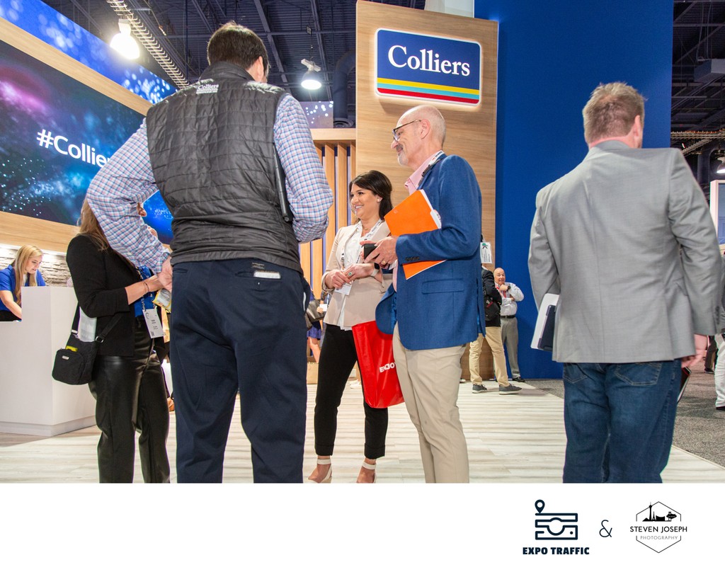 Colliers real estate booth at Las Vegas convention with busy trade show floor and attendees networking