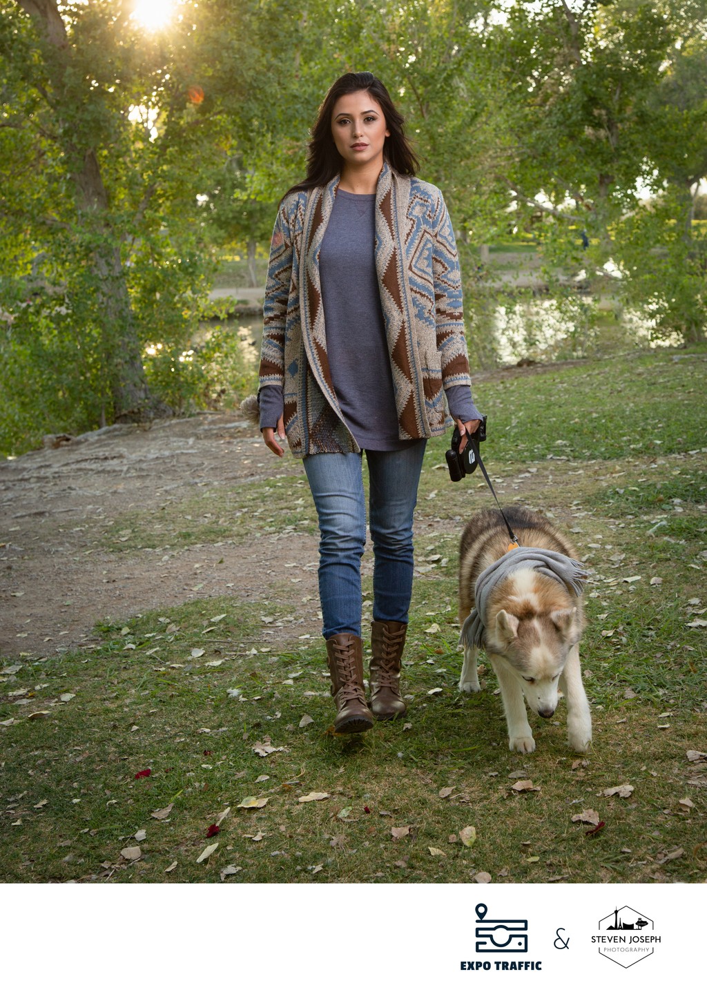 Beautiful auburn-haired woman walking with her dog in a park, fall sweater