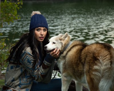 a beautiful woman and her dog by a pond in the fall
