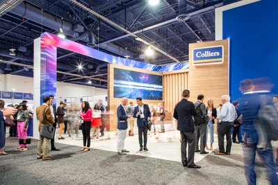 people in front of Colliers real estate booth at Las Vegas convention some blurred some sharp everyone networking