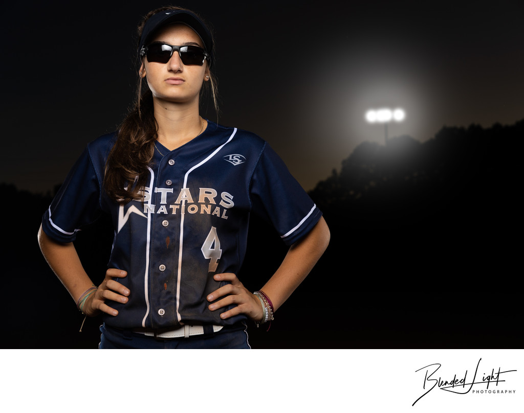Softball player portrait under the lights on field