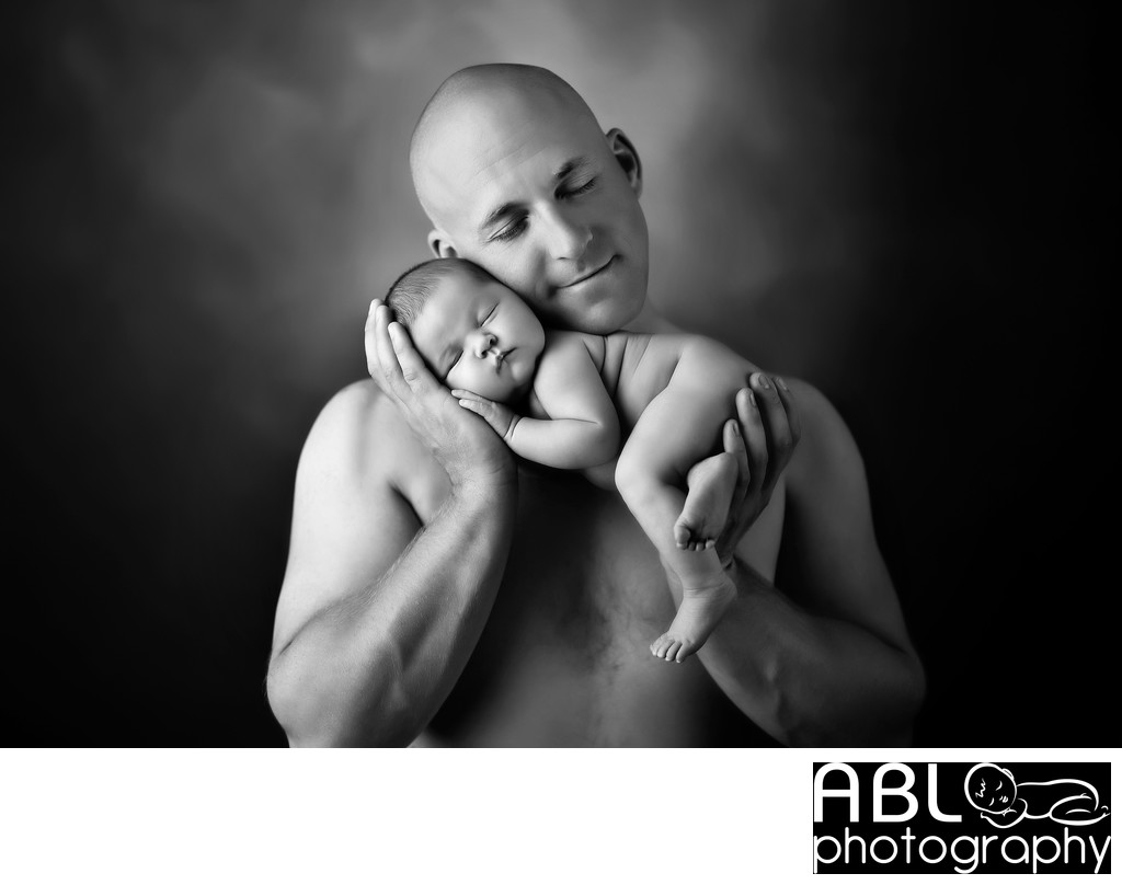 Shirtless man holding newborn baby 
