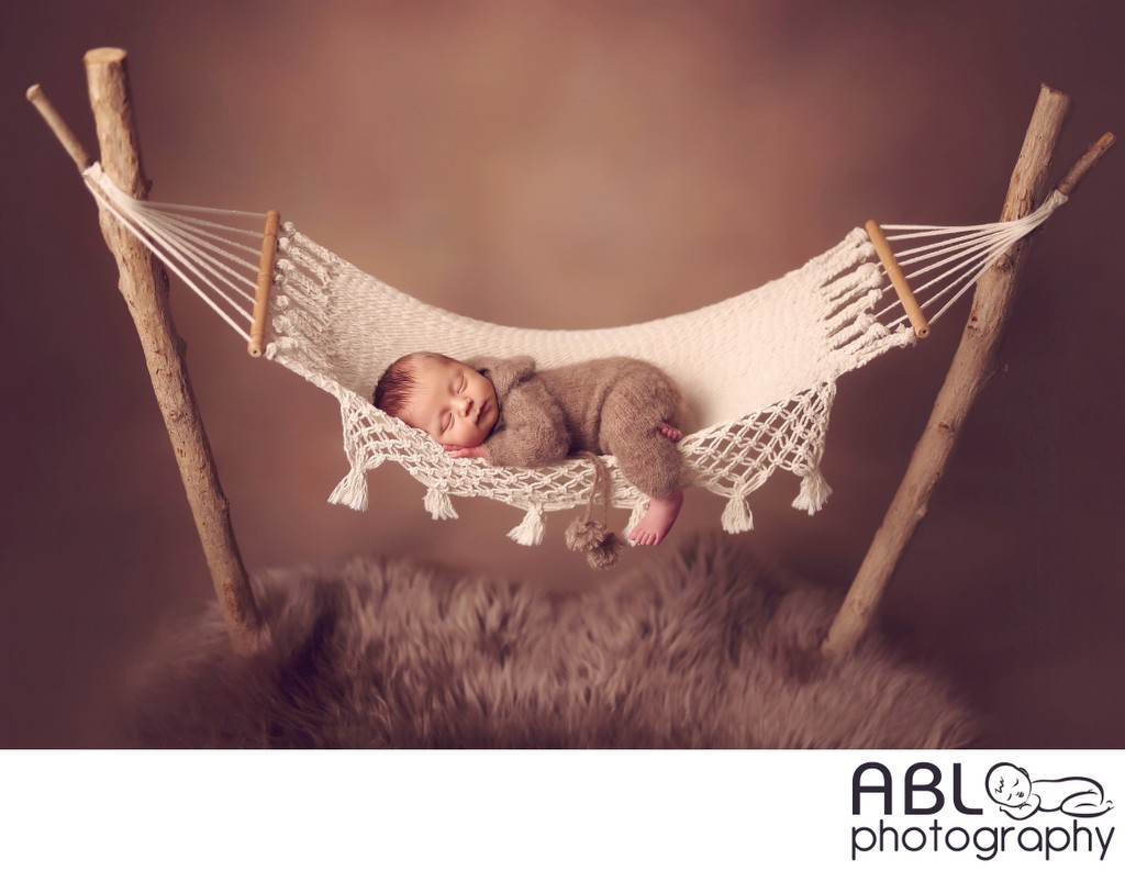 Baby in cream hammock on brown background