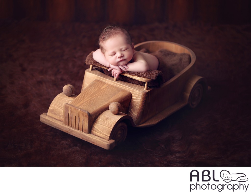 Newborn baby on wooden car