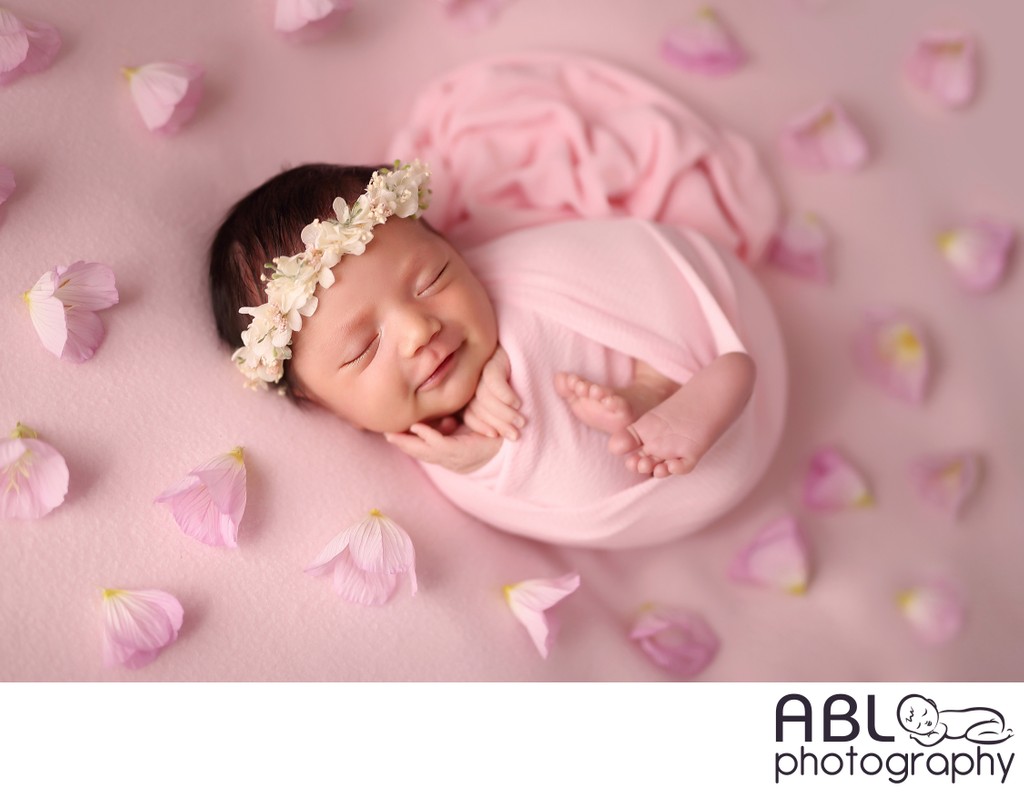 smiling baby girl on pink with flowers