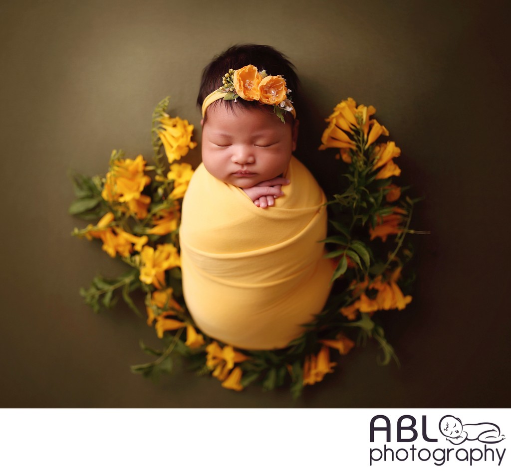 Newborn baby on green with yellow flowers