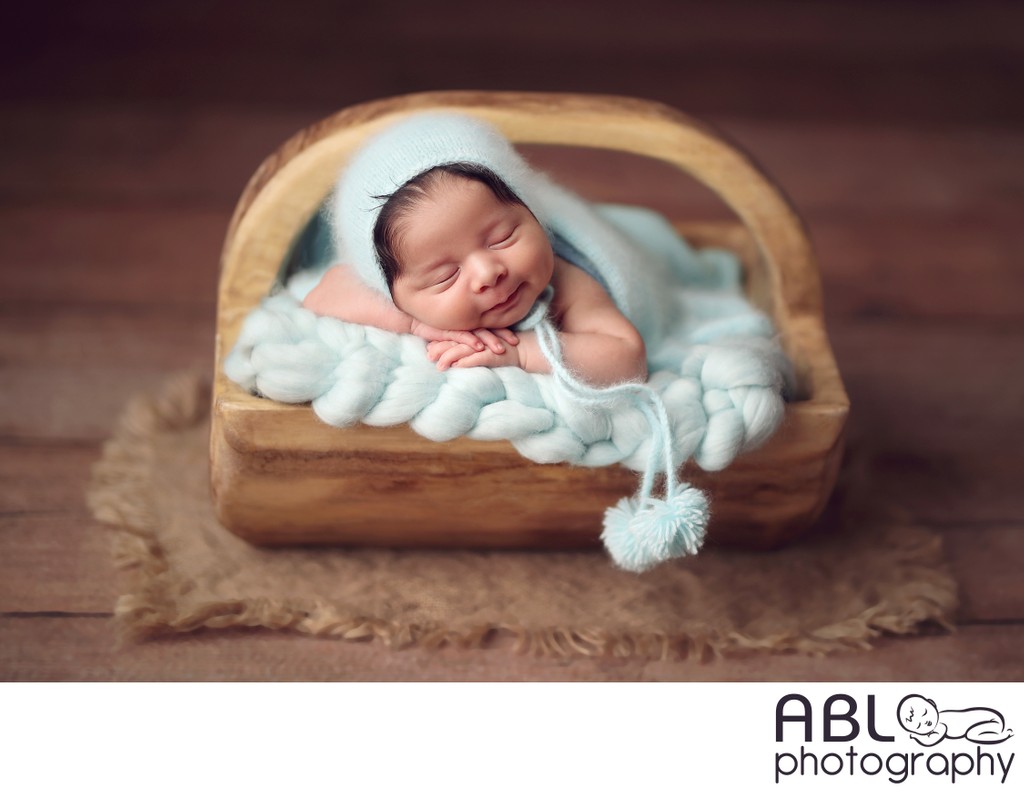 smiling baby boy in wooden bucket