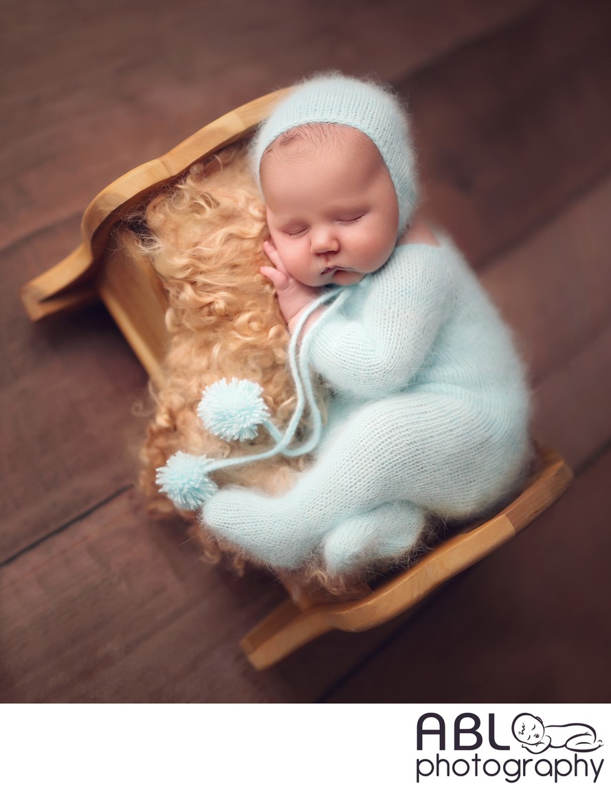 baby boy in aqua outfit on little bed