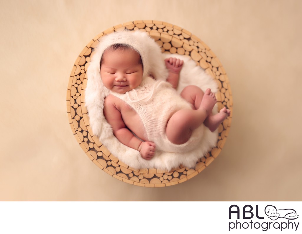 baby girl smiling in round wooden bowl