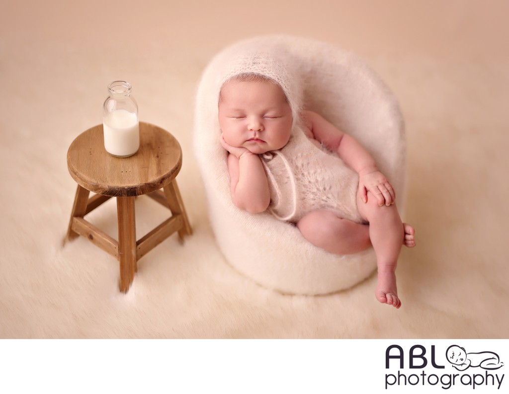 Baby in cream chair with milk bottle